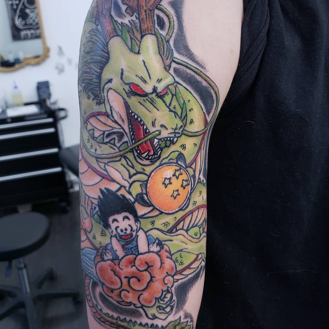 Colorful arm tattoo of Goku riding Shenron, surrounded by Dragon Balls and clouds
