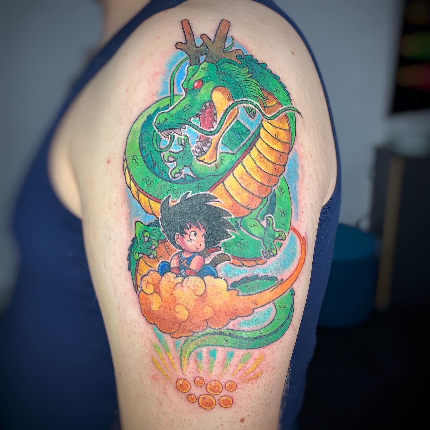 Vibrant arm tattoo of Shenron with young Goku on Nimbus, surrounded by Dragon Balls