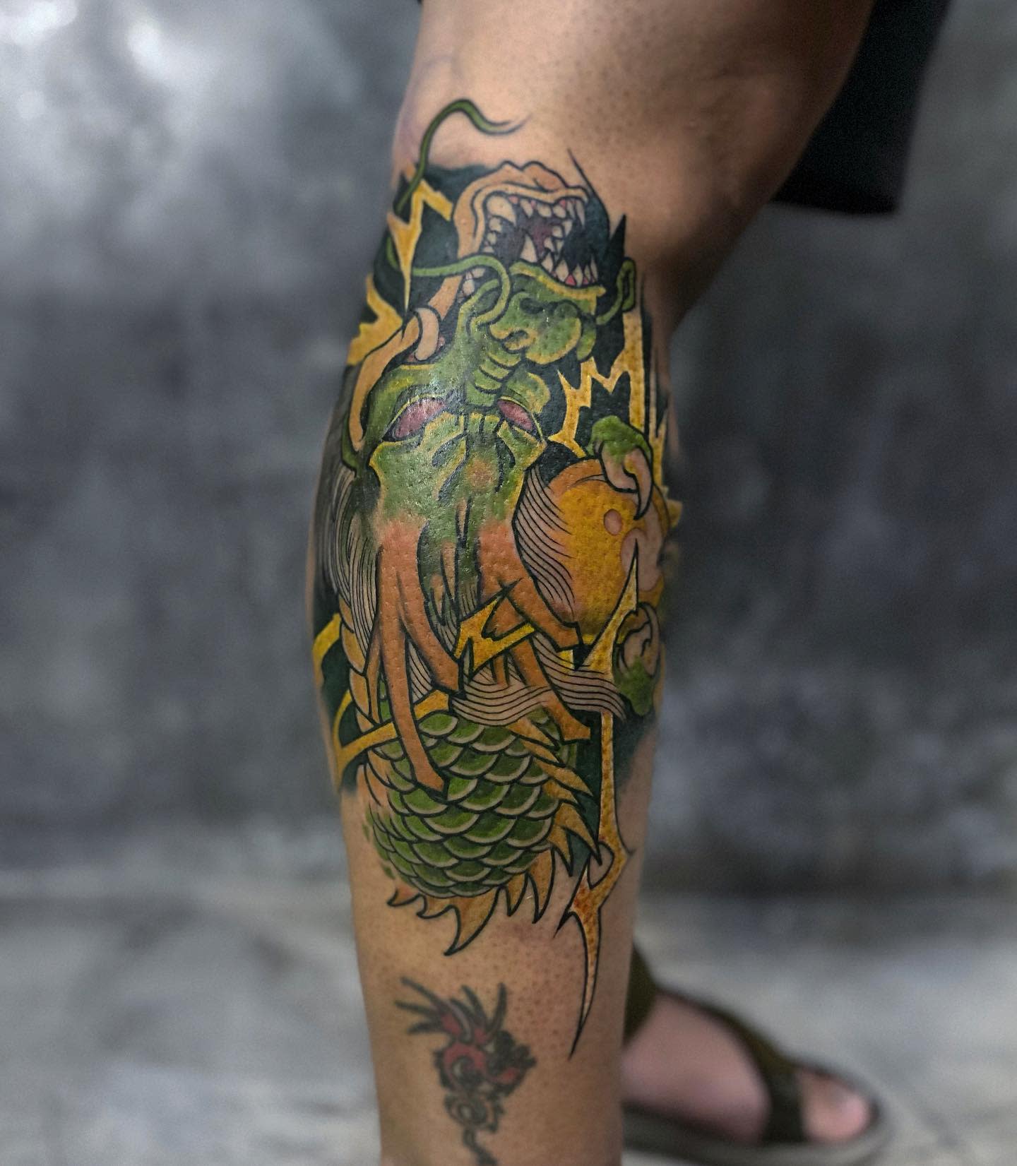 Intense and vibrant Shenron tattoo wrapping around the leg, showcasing rich colors and textures