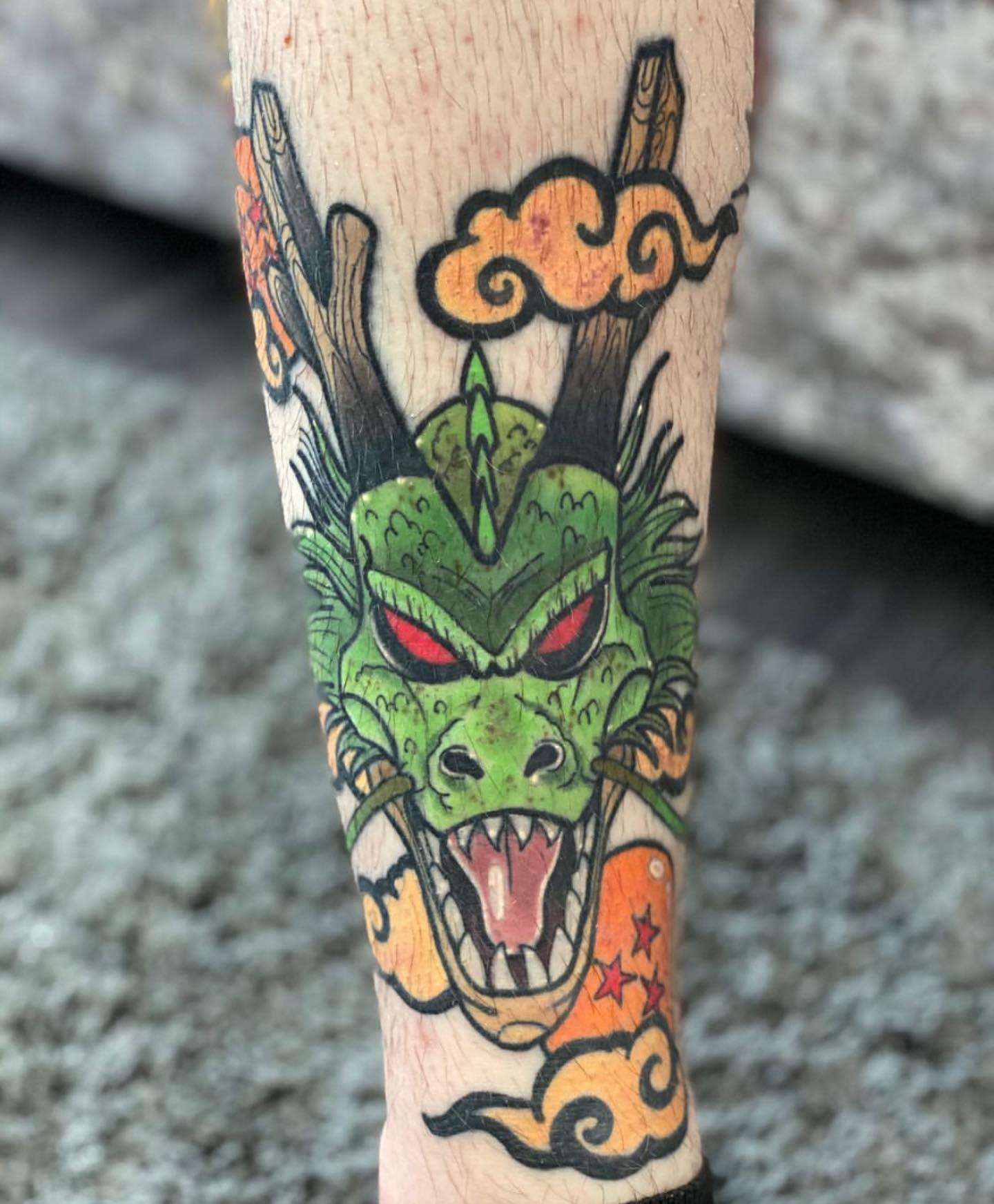 Bold tattoo of Shenron's face on the leg, surrounded by Dragon Balls and swirling clouds
