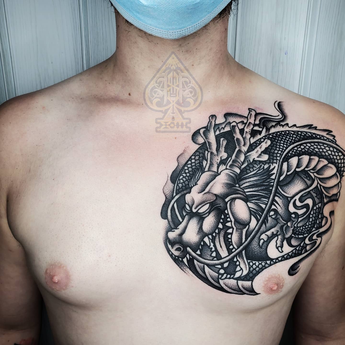 Intricate black and grey tattoo of Shenron on the chest, featuring fine dotwork and shading for depth