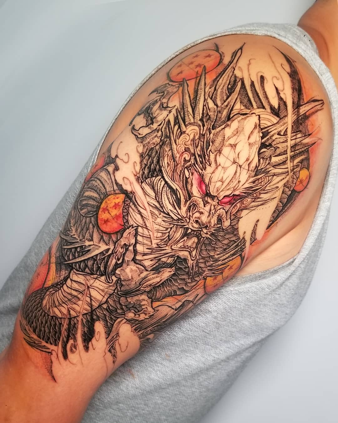 Complex shoulder tattoo featuring Shenron with intricate linework, shading, and vibrant Dragon Balls