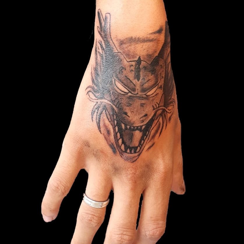 A detailed black and grey tattoo of Shenron's fierce face on the back of the hand, with intense shading