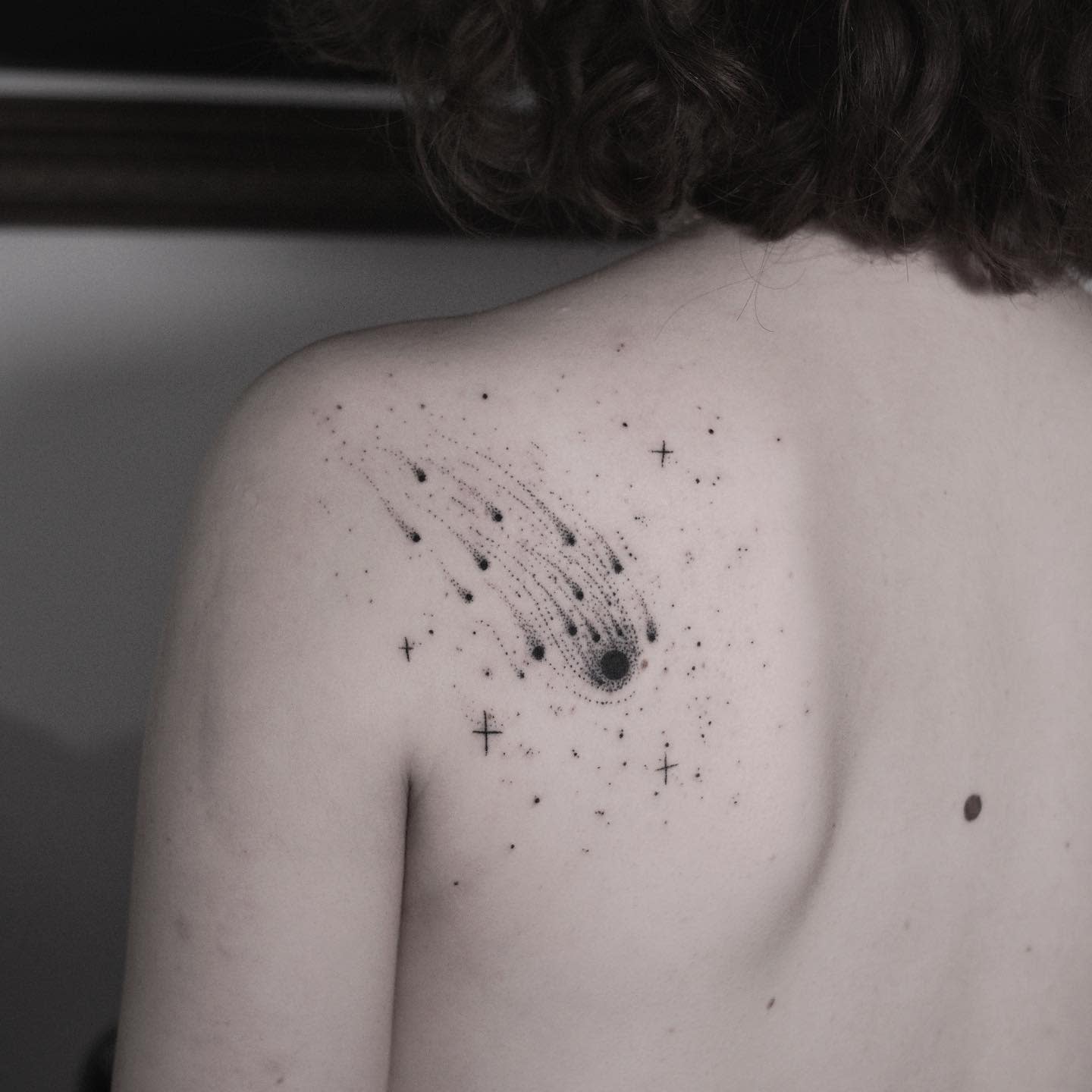 Back tattoo of a minimalist comet and stars on a shoulder