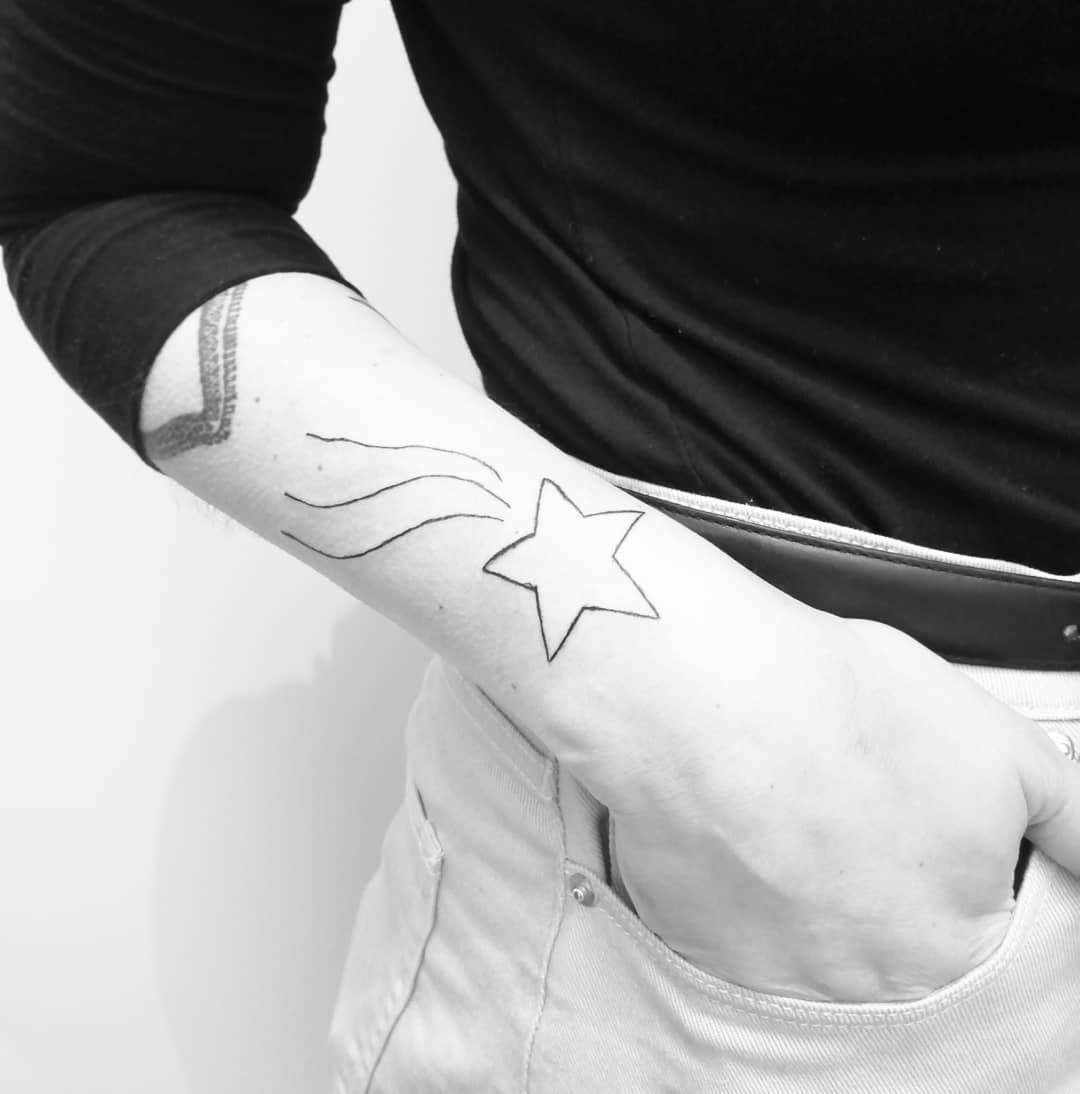 Black and white image of an arm with a star and shooting star tattoo