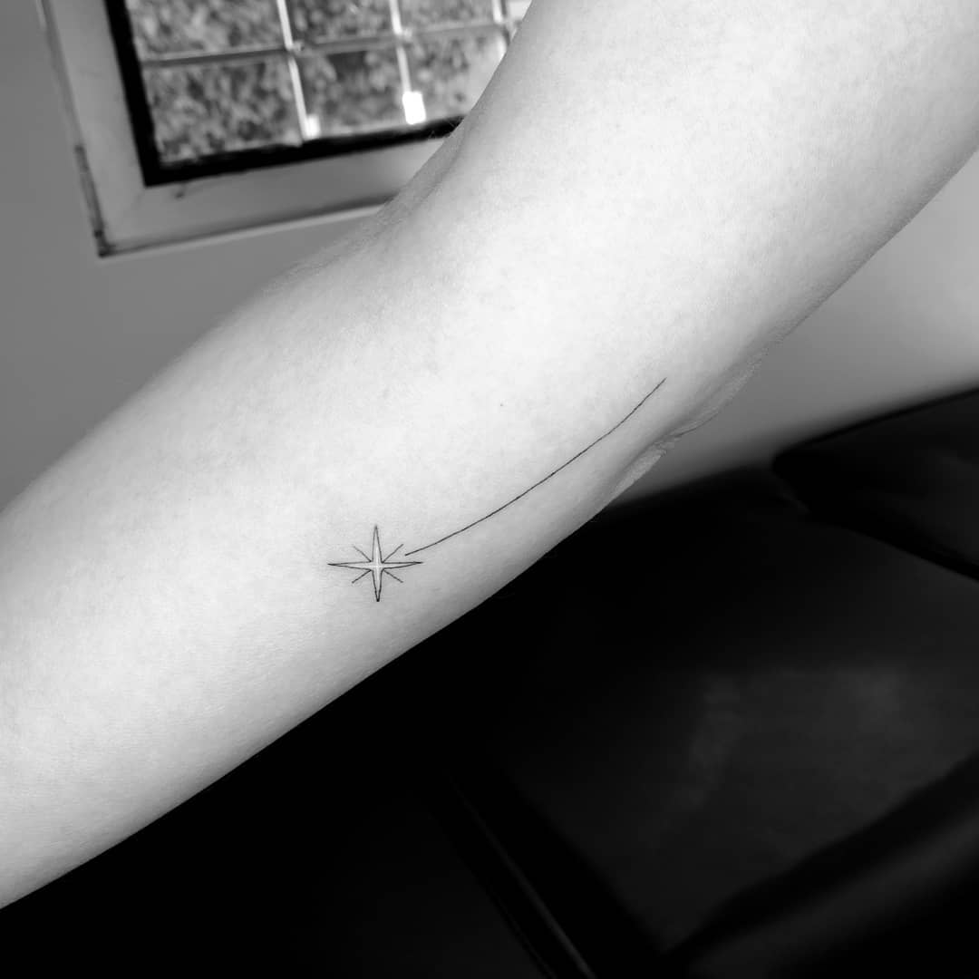 Minimalist shooting star tattoo on an arm
