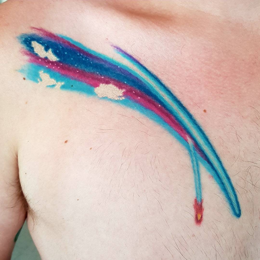 Abstract colorful brushstroke tattoo on chest featuring blue, pink, and cream colors