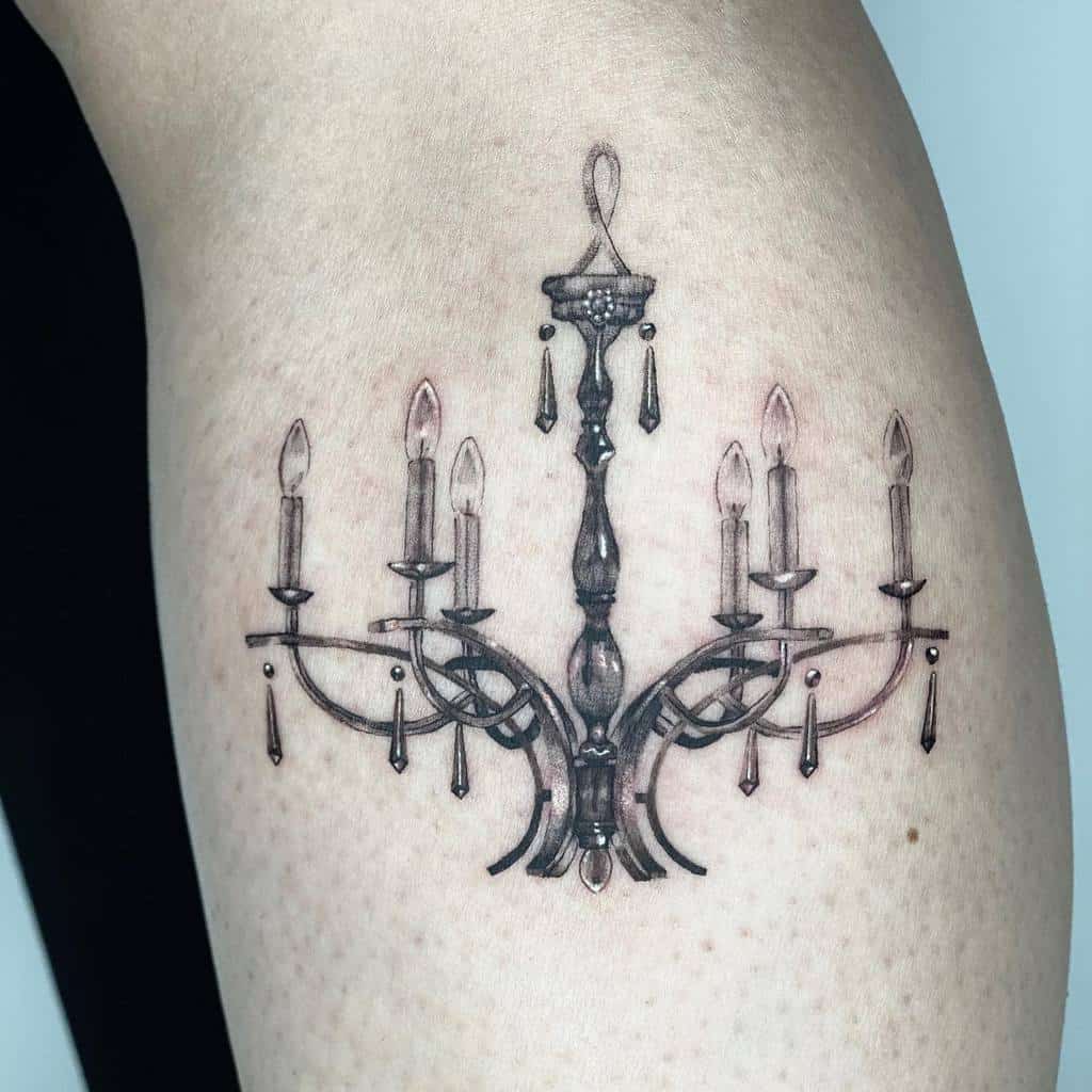 Realistic black and grey tattoo of a vintage chandelier with six candle lights, intricate metal details, and dangling crystal accents
