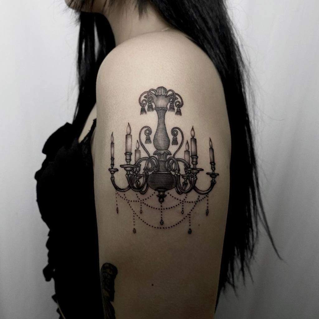 Black and grey tattoo of an ornate chandelier with six lit candles and hanging beads