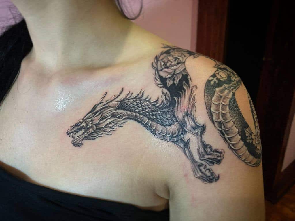 A dragon tattoo gracefully winding across a woman's shoulder and upper arm, showcasing its dynamic posture and intricate detailing