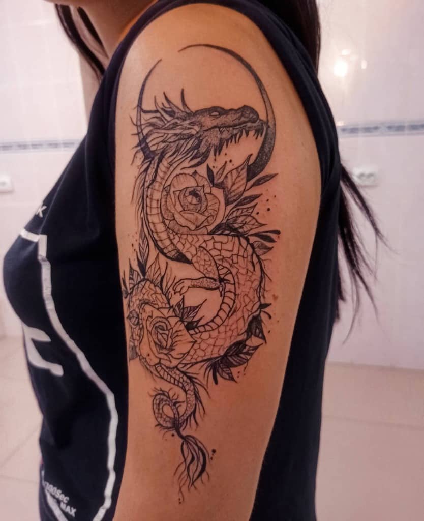 Dragon tattoo with roses on a woman's upper arm