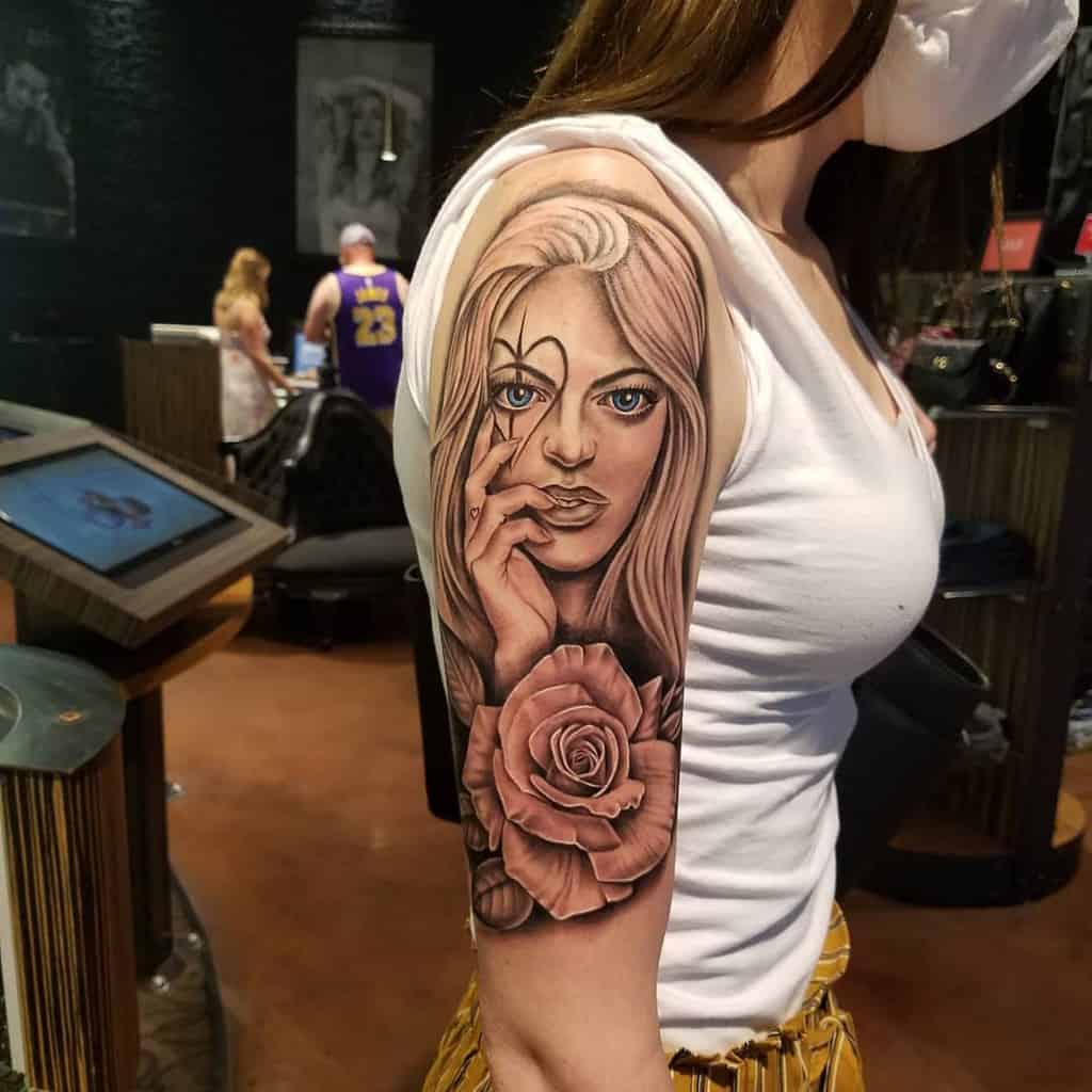 Woman with a detailed tattoo of a face and rose on her upper arm