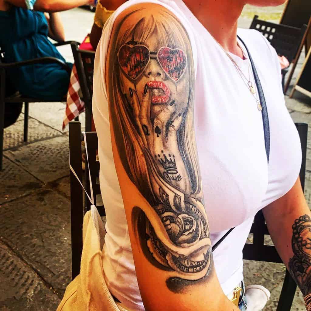 A woman with a tattoo of a woman in sunglasses and dollars on her arm