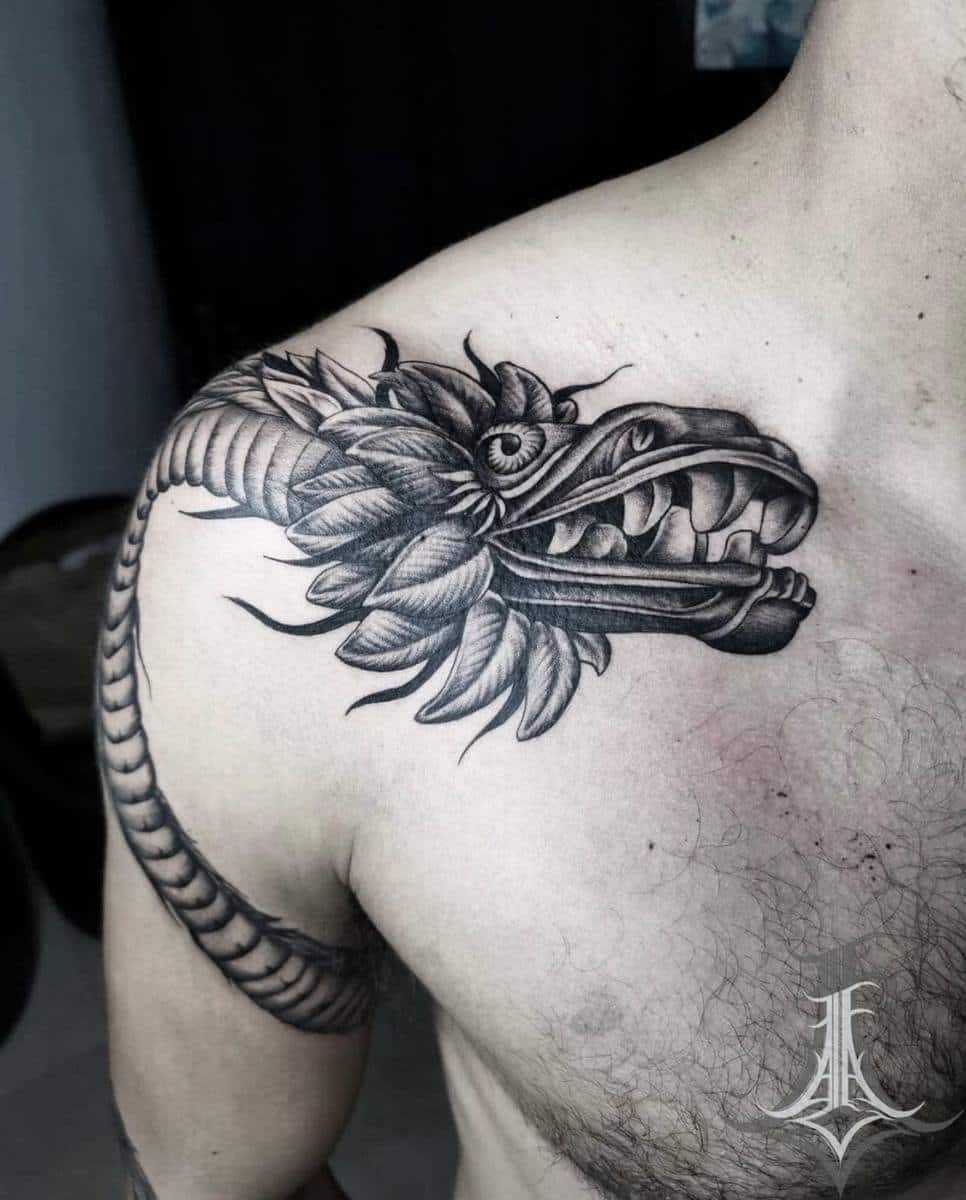 Black and grey shoulder tattoo of Quetzalcoatl featuring detailed feathers and serpent head