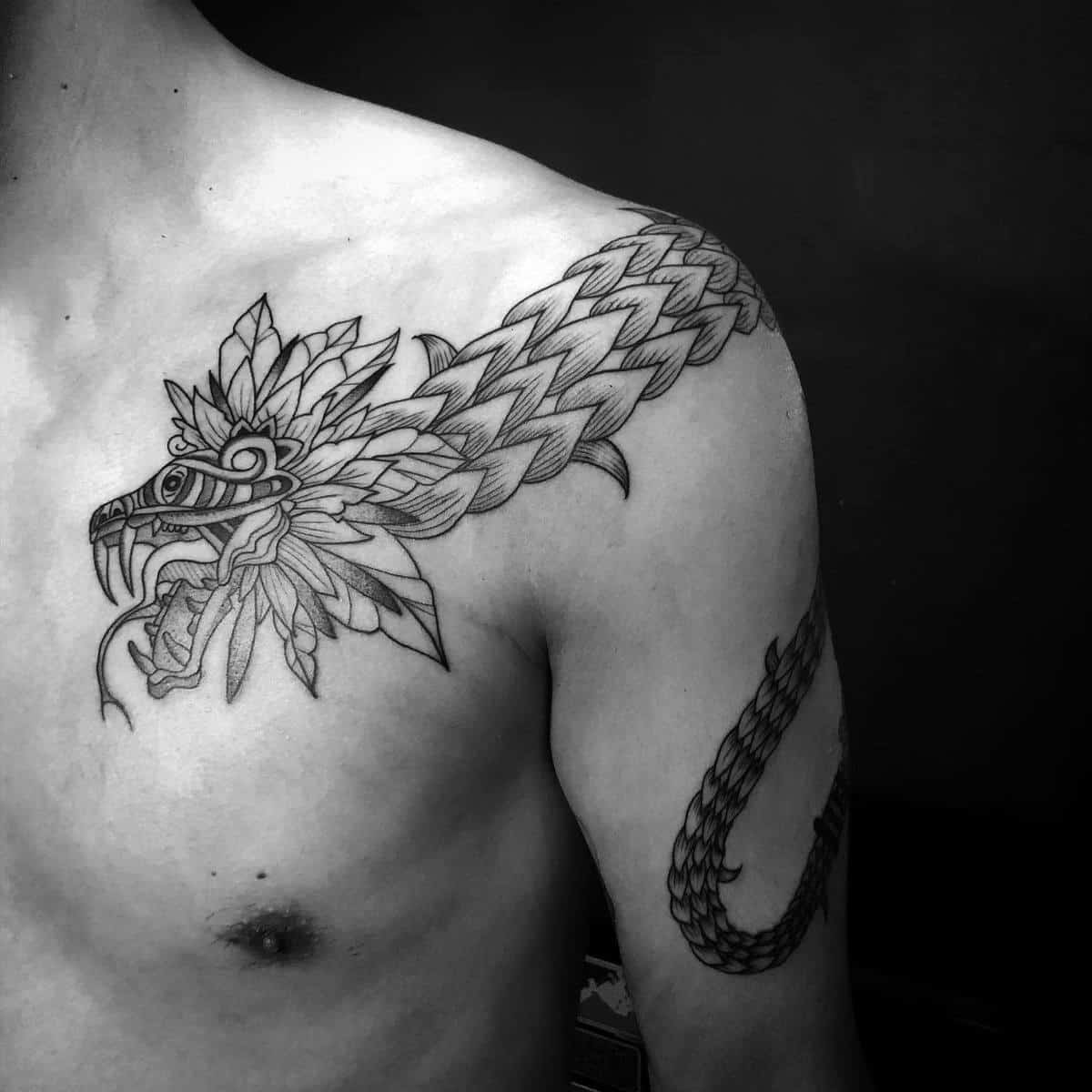 Linework tattoo of Quetzalcoatl on the shoulder, featuring detailed feathers and serpent body