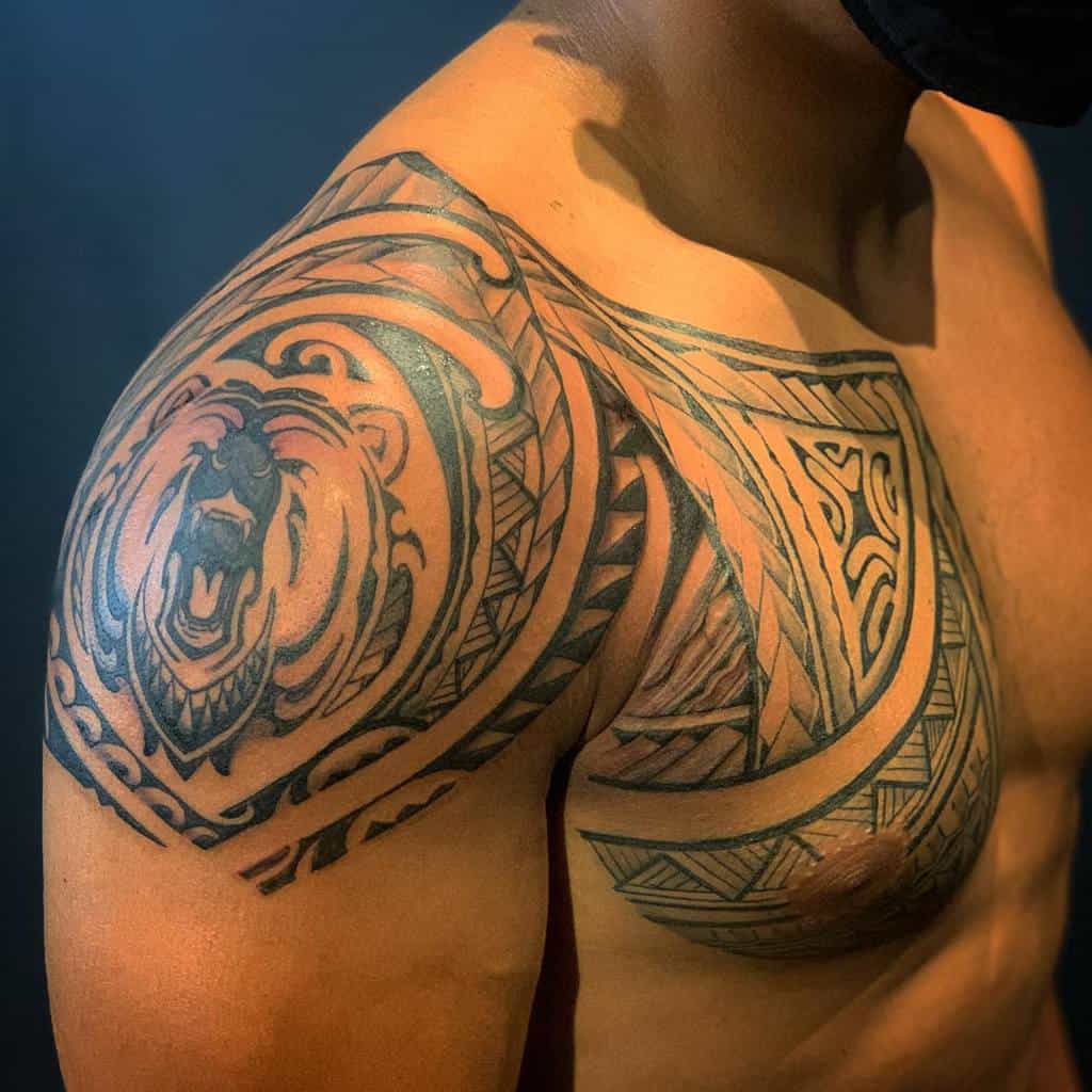 A man showcases a detailed tribal shoulder tattoo with a roaring bear design intertwined with striking Polynesian patterns