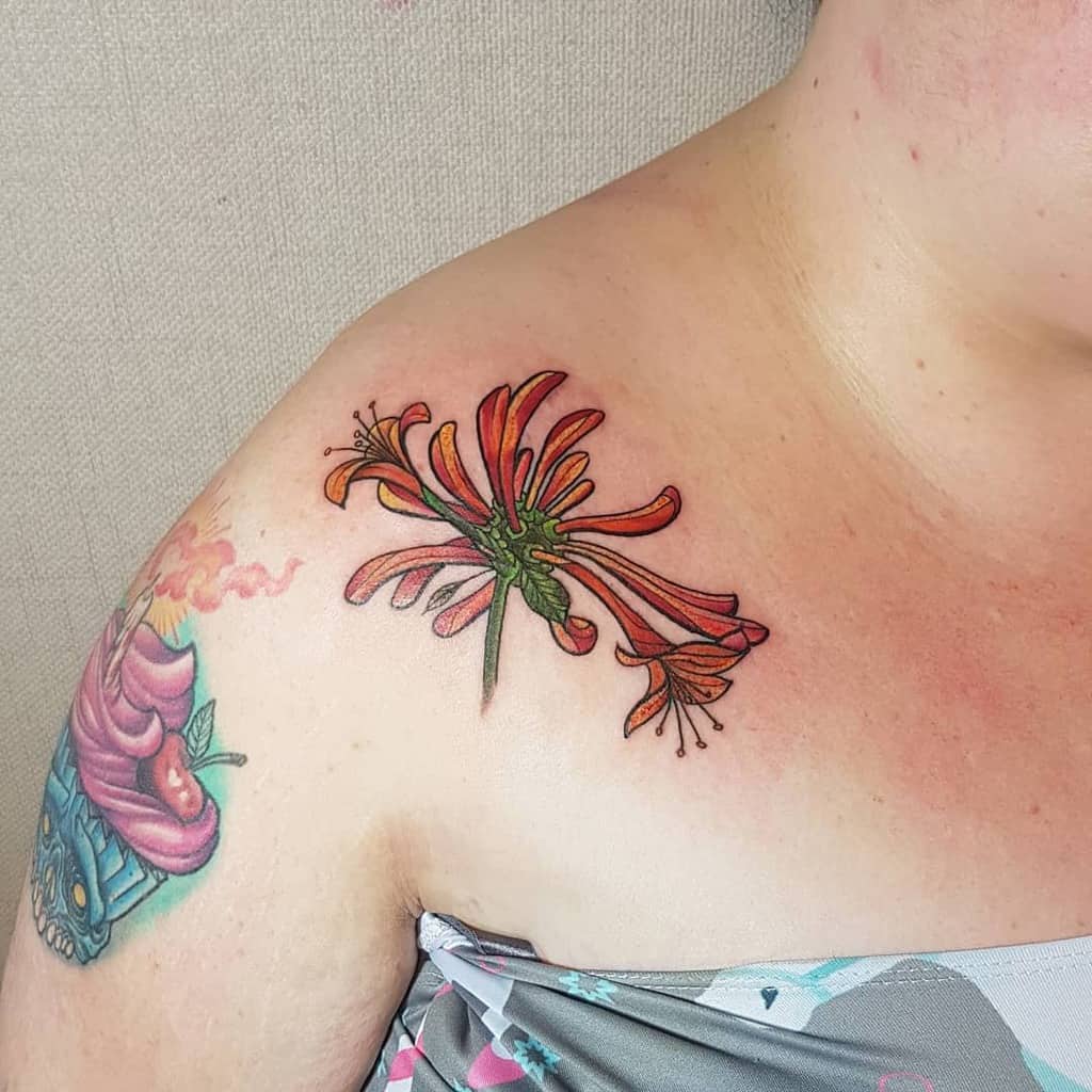 A vibrant honeysuckle flower tattoo on a shoulder