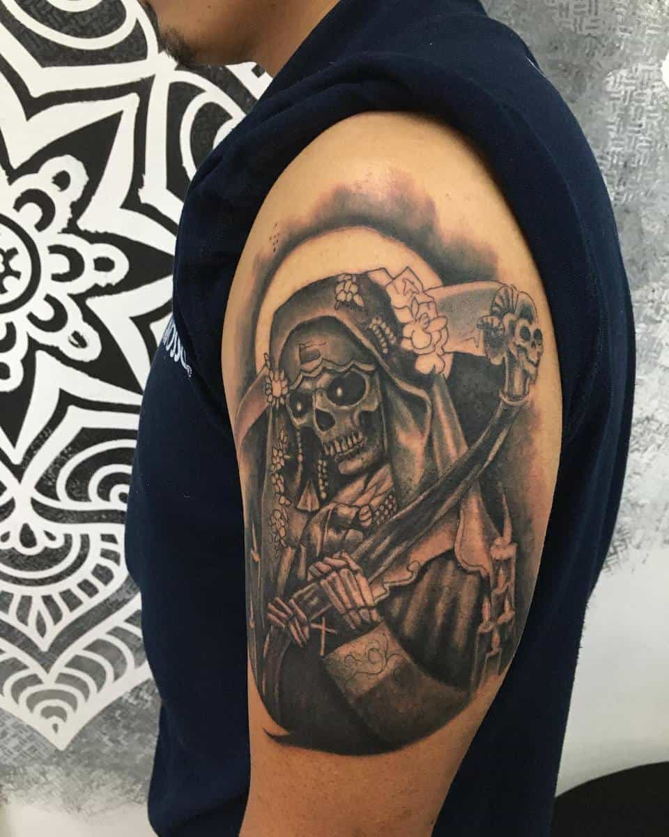 Santa Muerte tattoo on the upper arm, featuring a hooded skeleton with a scythe, symbolizing protection and devotion