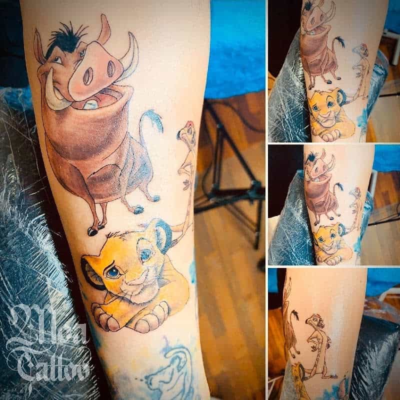 Colorful tattoo depicting Simba, Timon, and Pumbaa in various poses, capturing their playful personalities with vibrant shading and intricate details