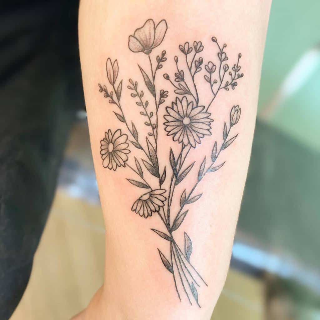 A delicate black line bouquet tattoo featuring asters and wildflowers on the forearm