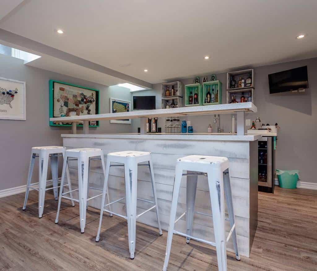 Whitewashed basement bar with metal stools, open shelving, and wood accents.