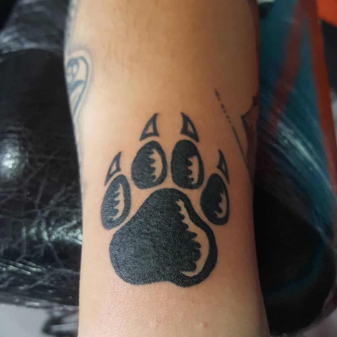 Tattoo of a striking bear paw with realistic claw marks etched on an arm