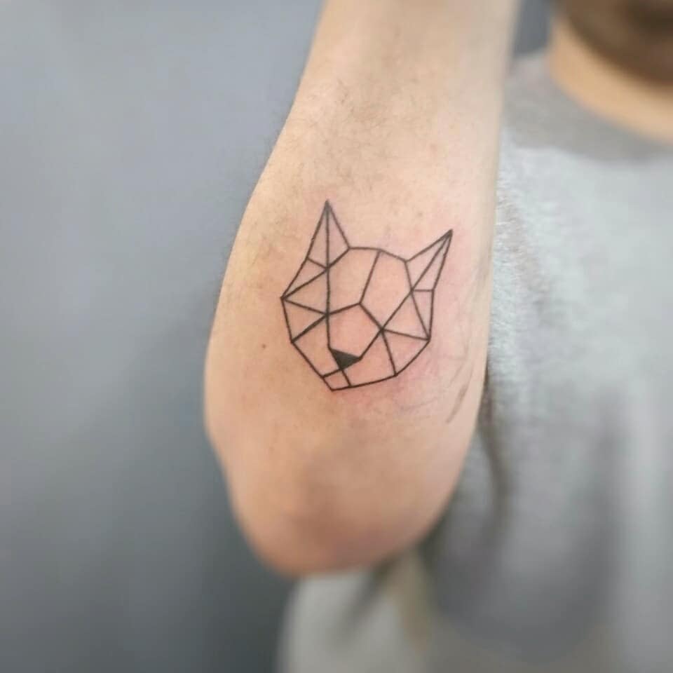 Geometric cat tattoo on a person's upper arm