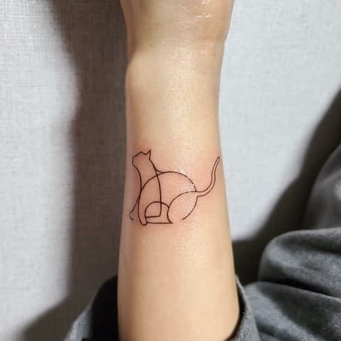 Elegant wrist tattoo of a sitting cat formed with geometric and continuous black line art