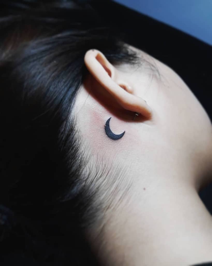 A small crescent moon tattoo behind ear
