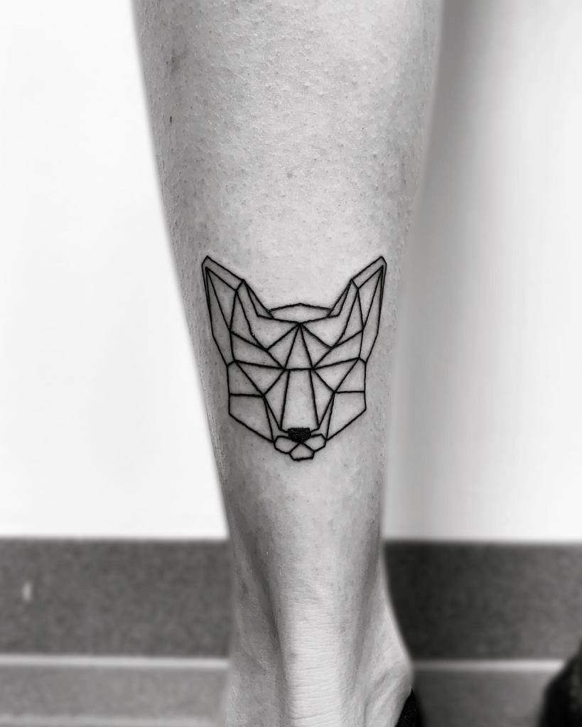 A stunning geometric fox tattoo adorns the back of a person's leg, blending artistry and precision in every line