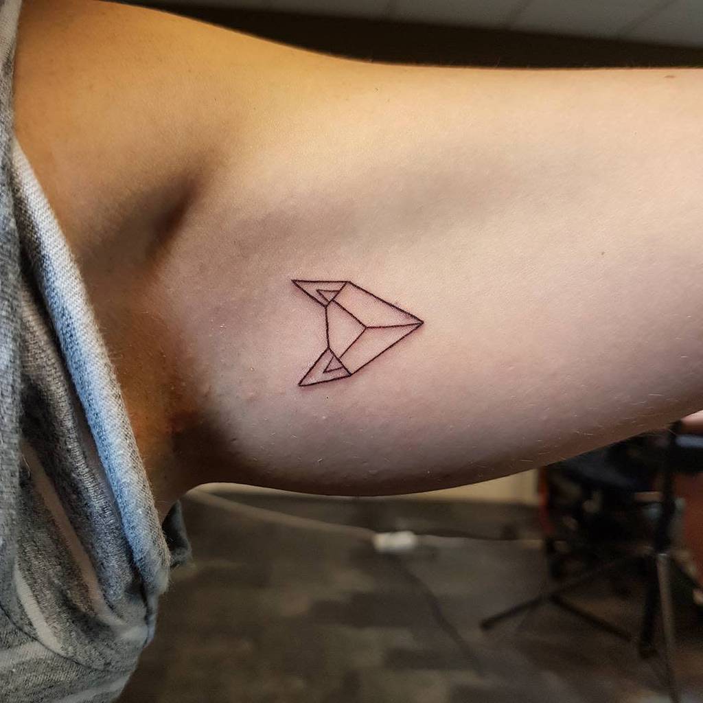 Simple geometric tattoo with triangular shapes and a stylized geometric fox on a person's inner upper arm