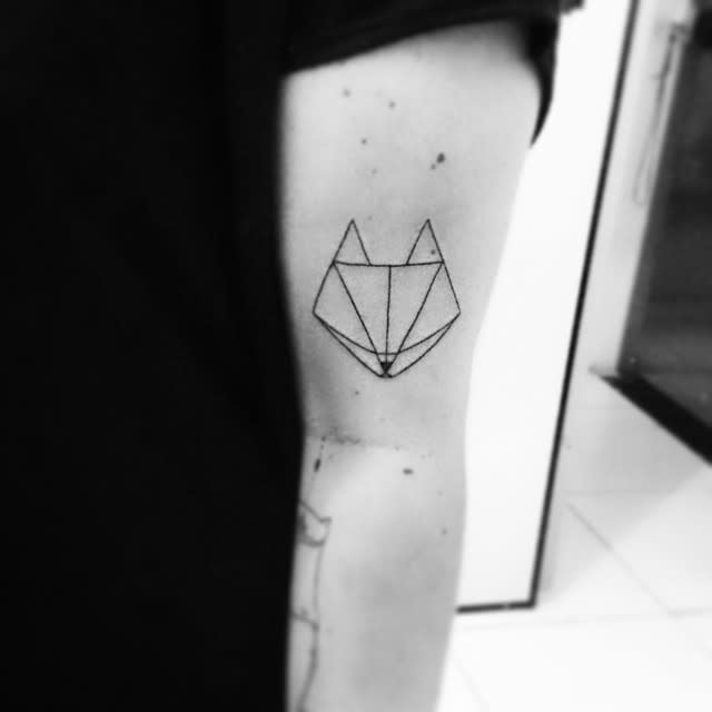 Sleek geometric fox tattoo in black ink on the upper arm