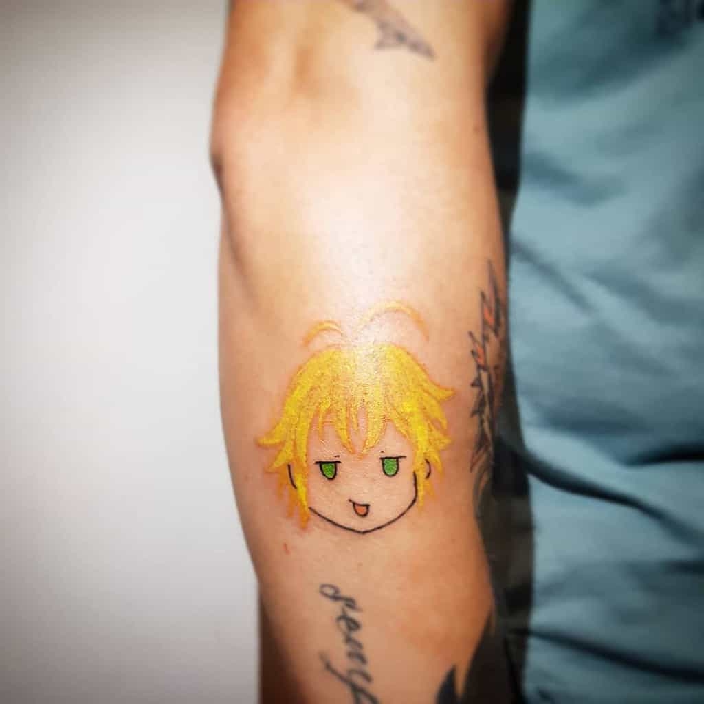 Colorful tattoo of a chibi-style Meliodas from The Seven Deadly Sins, featuring his signature spiky blonde hair and green eyes in a playful expression