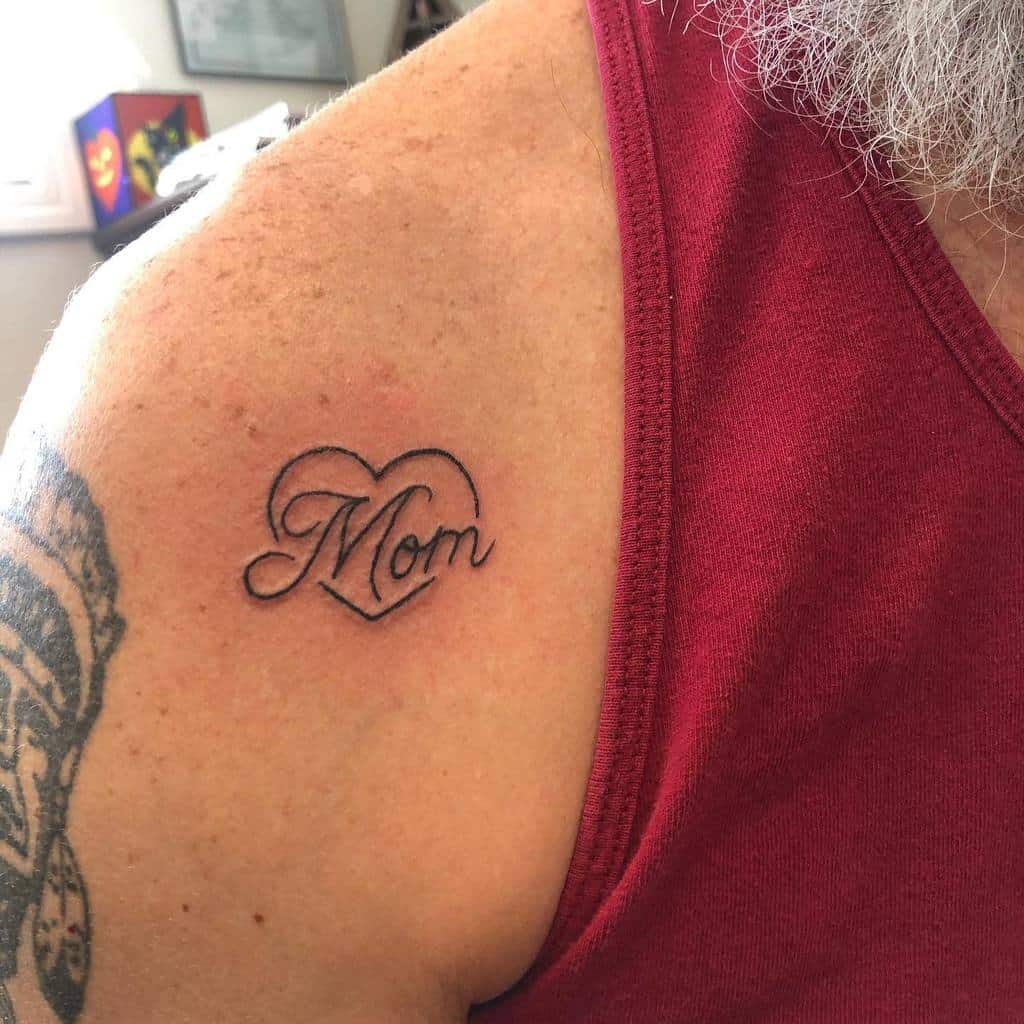 Tattoo of the word "Mom" elegantly inked within a heart on a shoulder