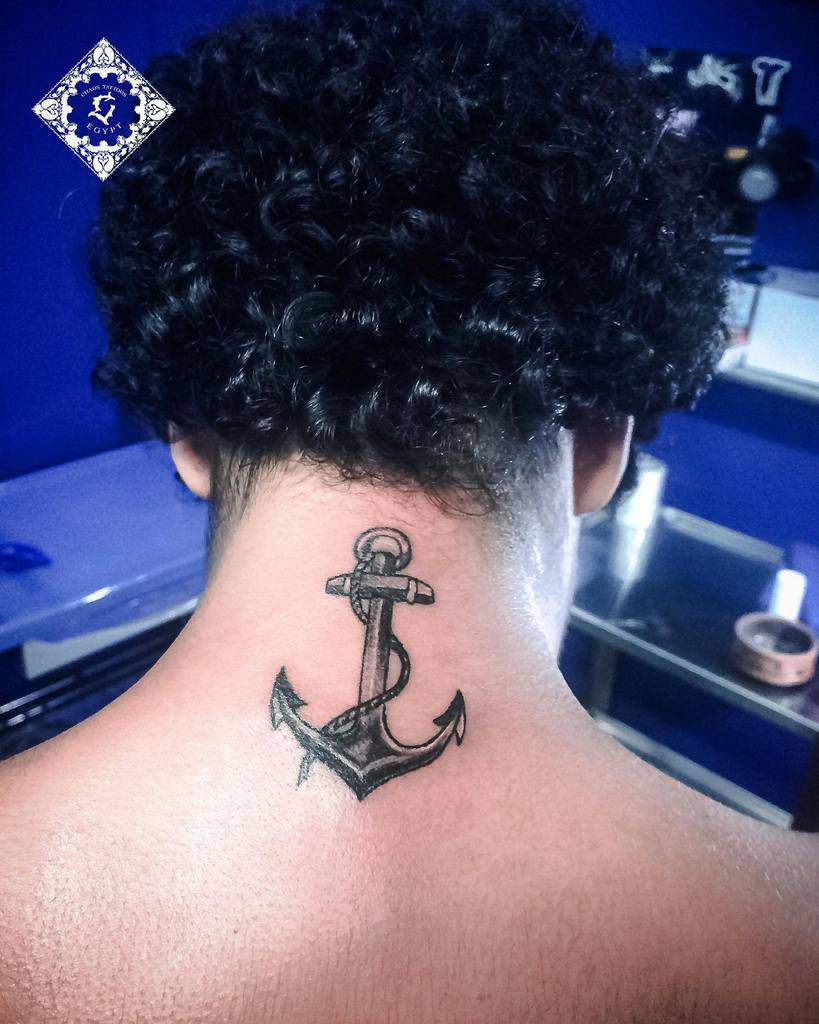 Navy anchor tattoo on the back of a person's neck