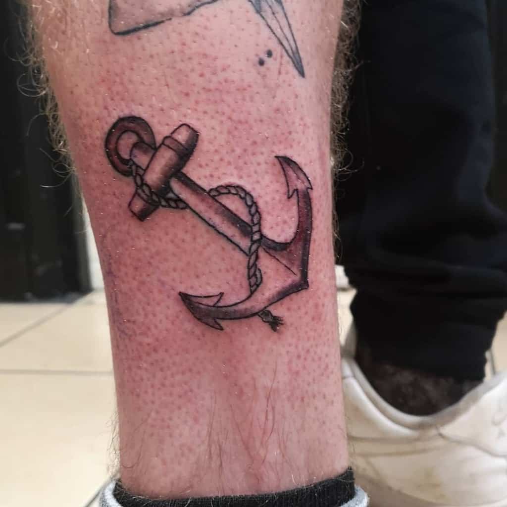 Tattoo of a navy anchor with a rope inked on the leg above the ankle