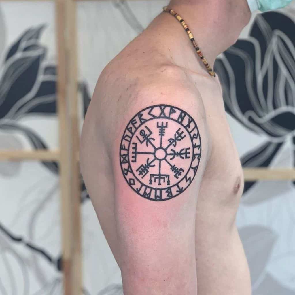 Tattoo of a Nordic protection symbol, Vegvisir, enclosed in a circular rune design on the upper arm.