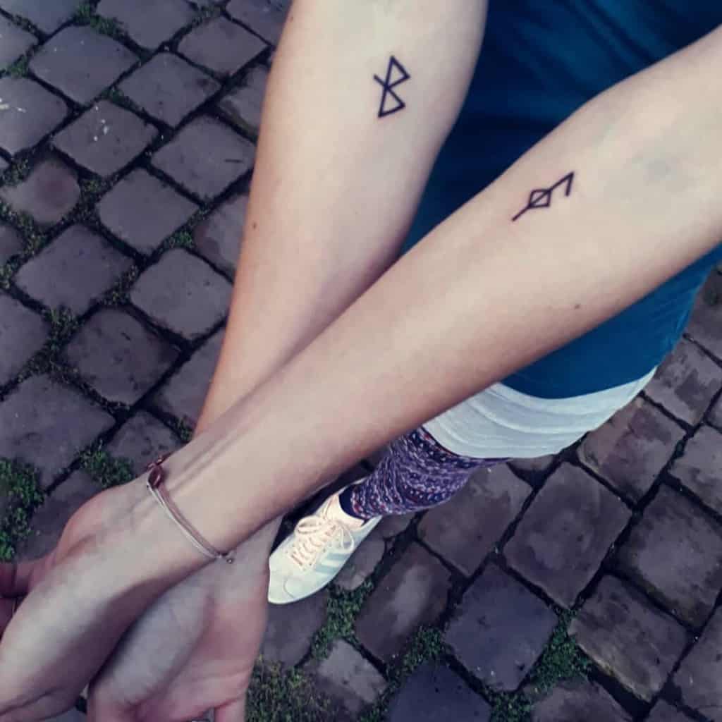 Tattoos of two minimalist Nordic-inspired symbols on the forearms