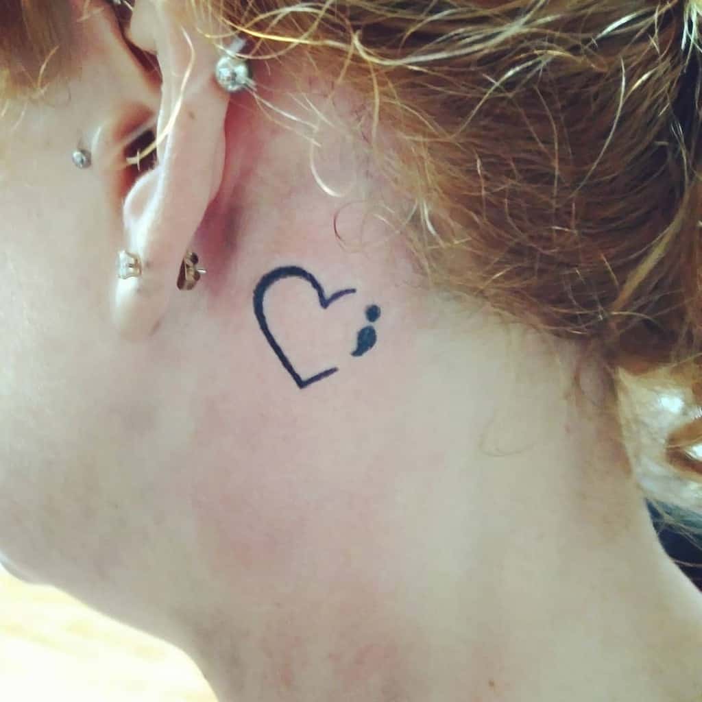 Simple and charming tattoo, featuring an outlined heart with a small dot, executed in black ink