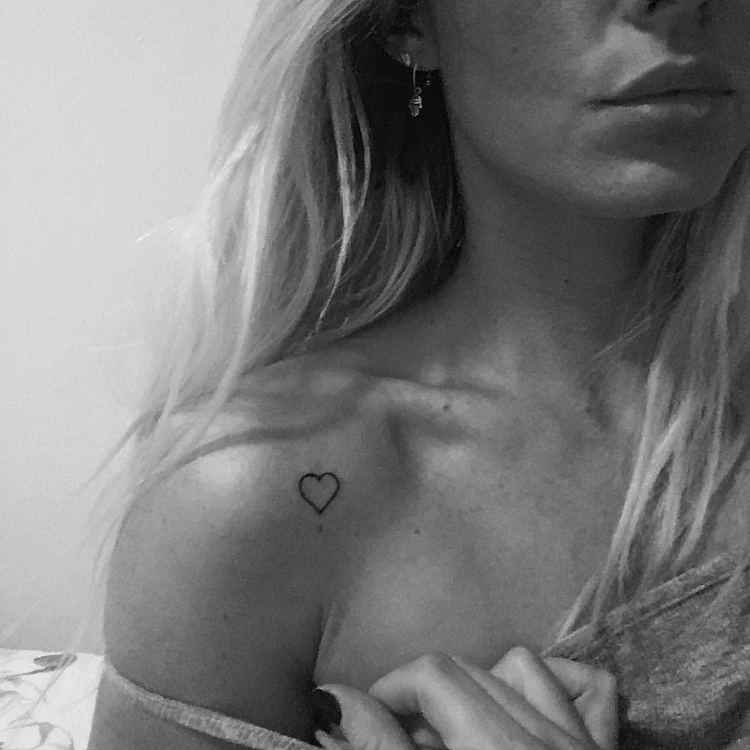 A small black heart tattoo, conveying a sense of simplicity and elegance
