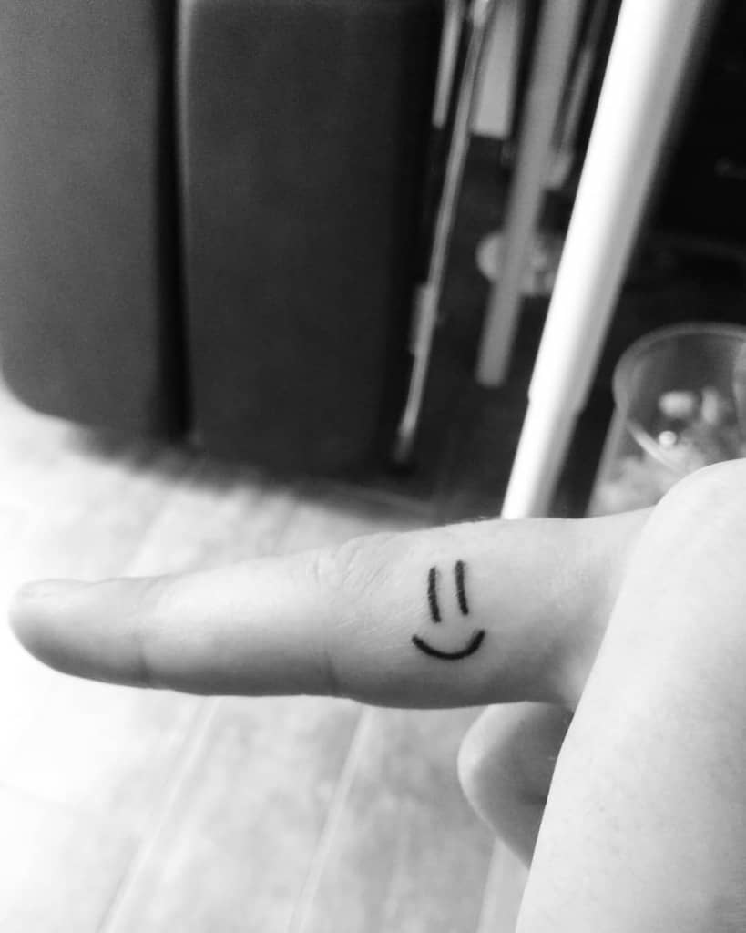 Smiley face tattoo on a finger