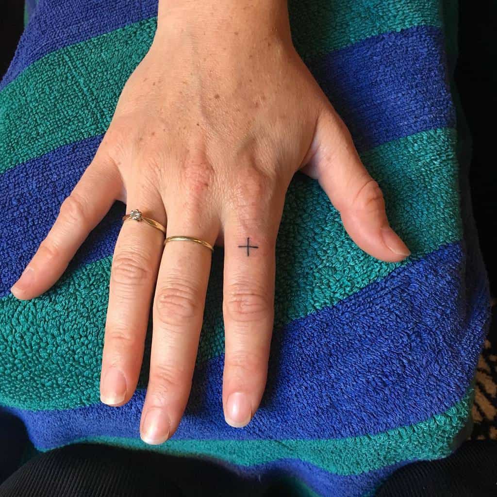 Hand with small cross tattoo on finger