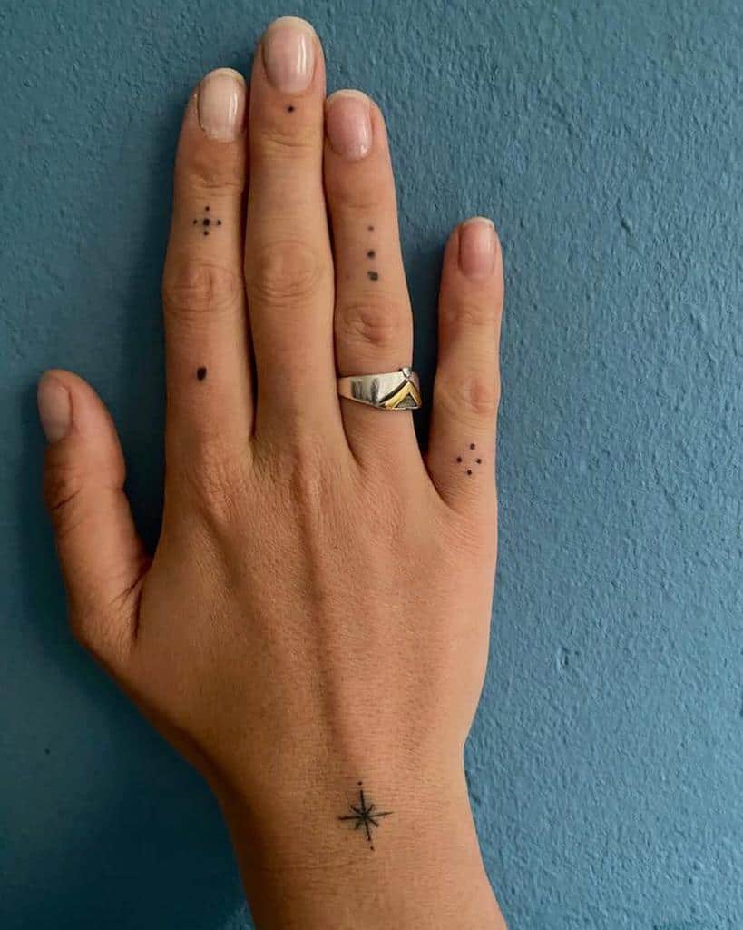 Hand with dot tattoos on fingers and a star tattoo on the wrist