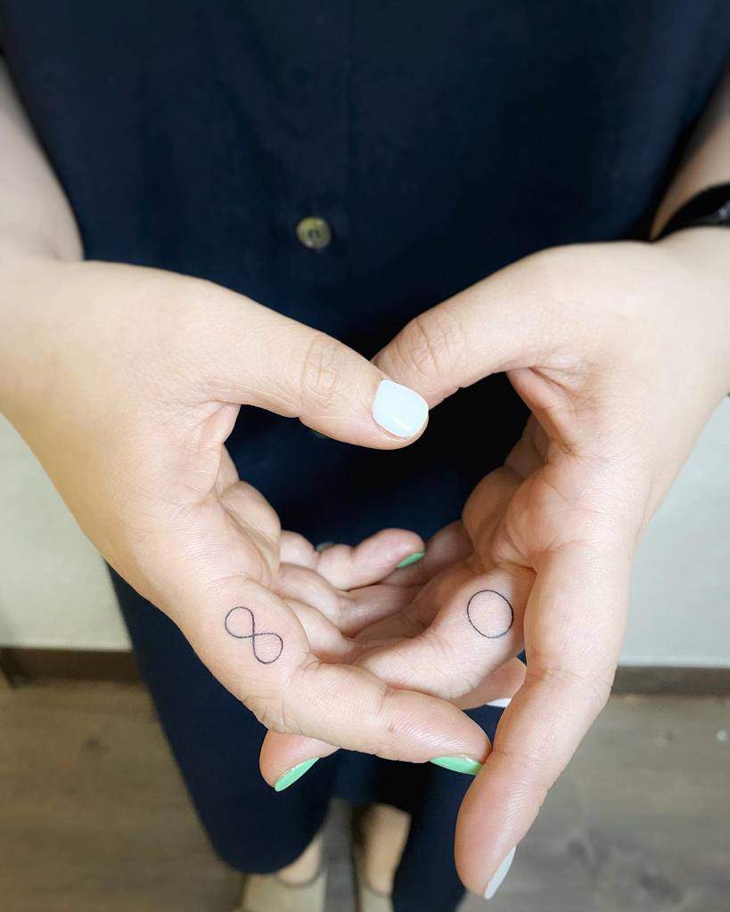 Small infinity tattoo on a finger and circle tattoo on another finger