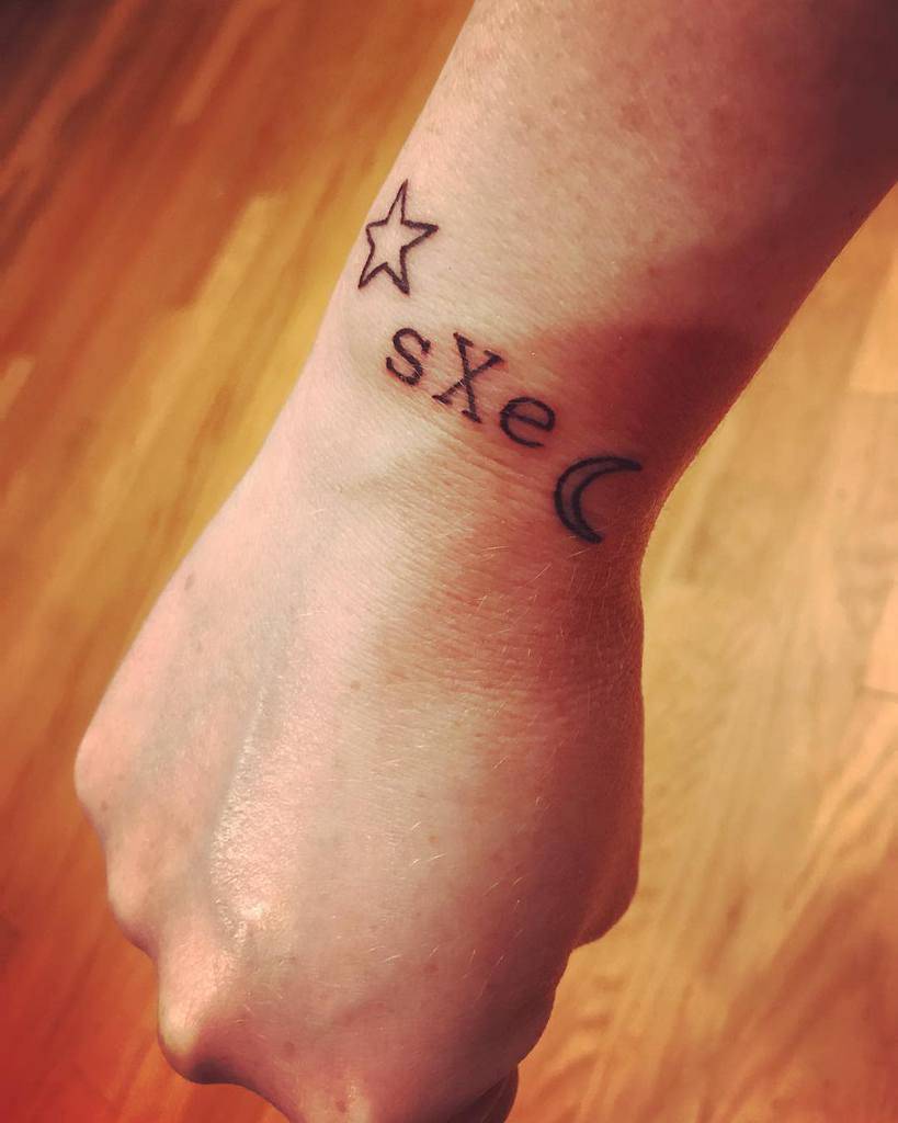 Minimalist straight edge (sXe) tattoo featuring a star, the 'sXe' acronym, and a crescent moon, symbolizing a commitment to a sober lifestyle