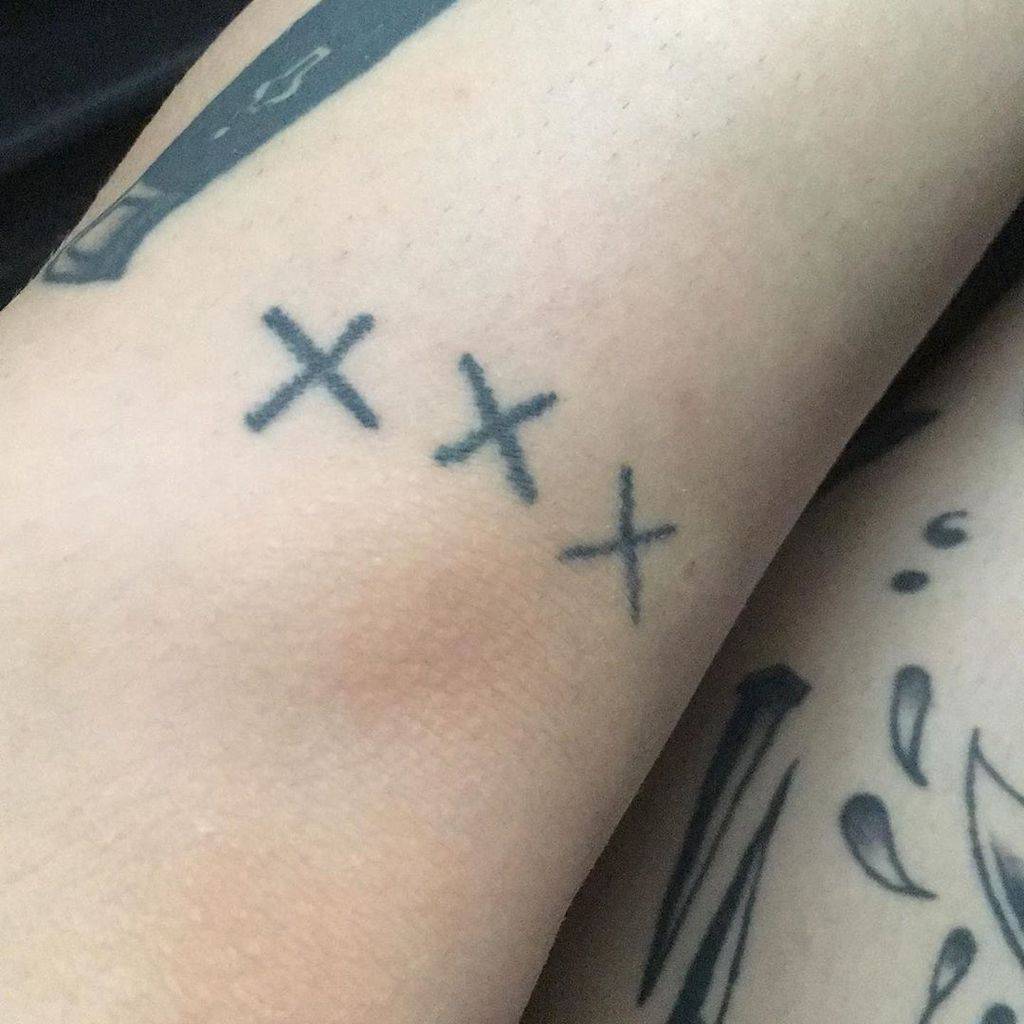 Minimalist straight edge tattoo with three simple black 'X' symbols, representing a commitment to a substance-free lifestyle