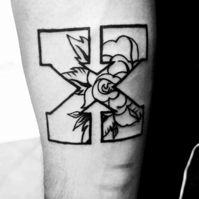 Black outline straight edge tattoo featuring a bold 'X' filled with a delicate rose and leaves, blending strength with elegance