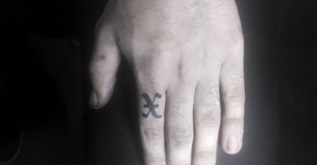 Minimalist straight edge tattoo featuring a small bold 'X' on the side of the finger