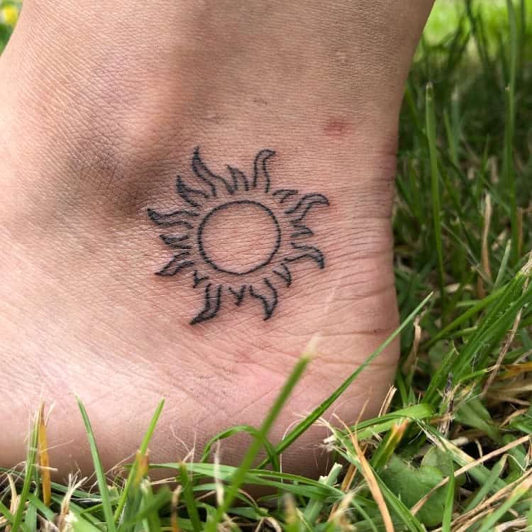 A black sun tattoo on an ankle