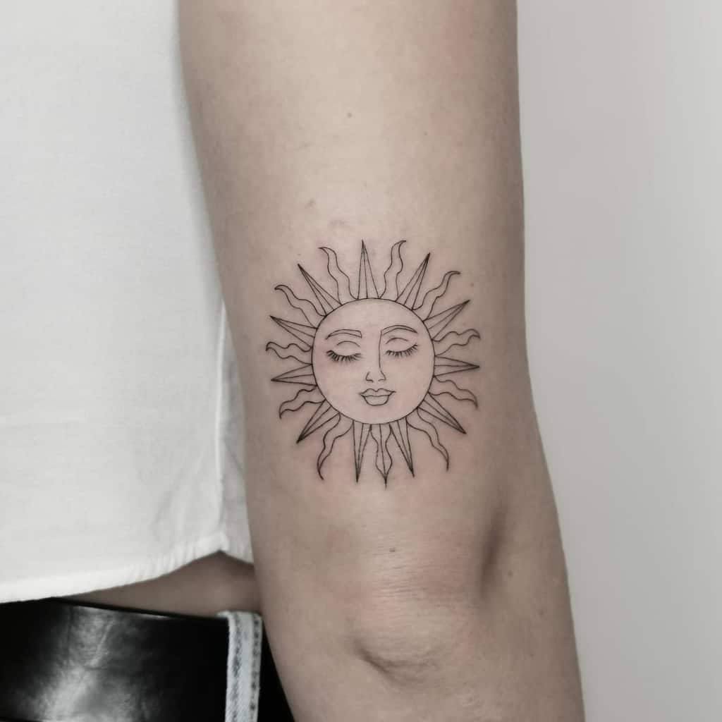 Tattoo of a sun with a face on an inner forearm, black ink, minimalistic design